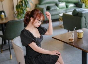 Young woman in a black dress enjoying a moment of relaxation in a Vietnamese cafe.